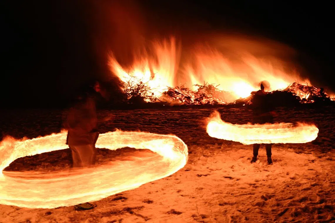 Revellers spining fireballs near a bonfire as Bulgarians celebrate Mesni Zagovezni, an Orthodox Christian holiday marking the start of Easter fasting, during which they chase away evil spirits with fire rituals, in the village of Lozen, Bulgaria, on Feb 23, 2025.