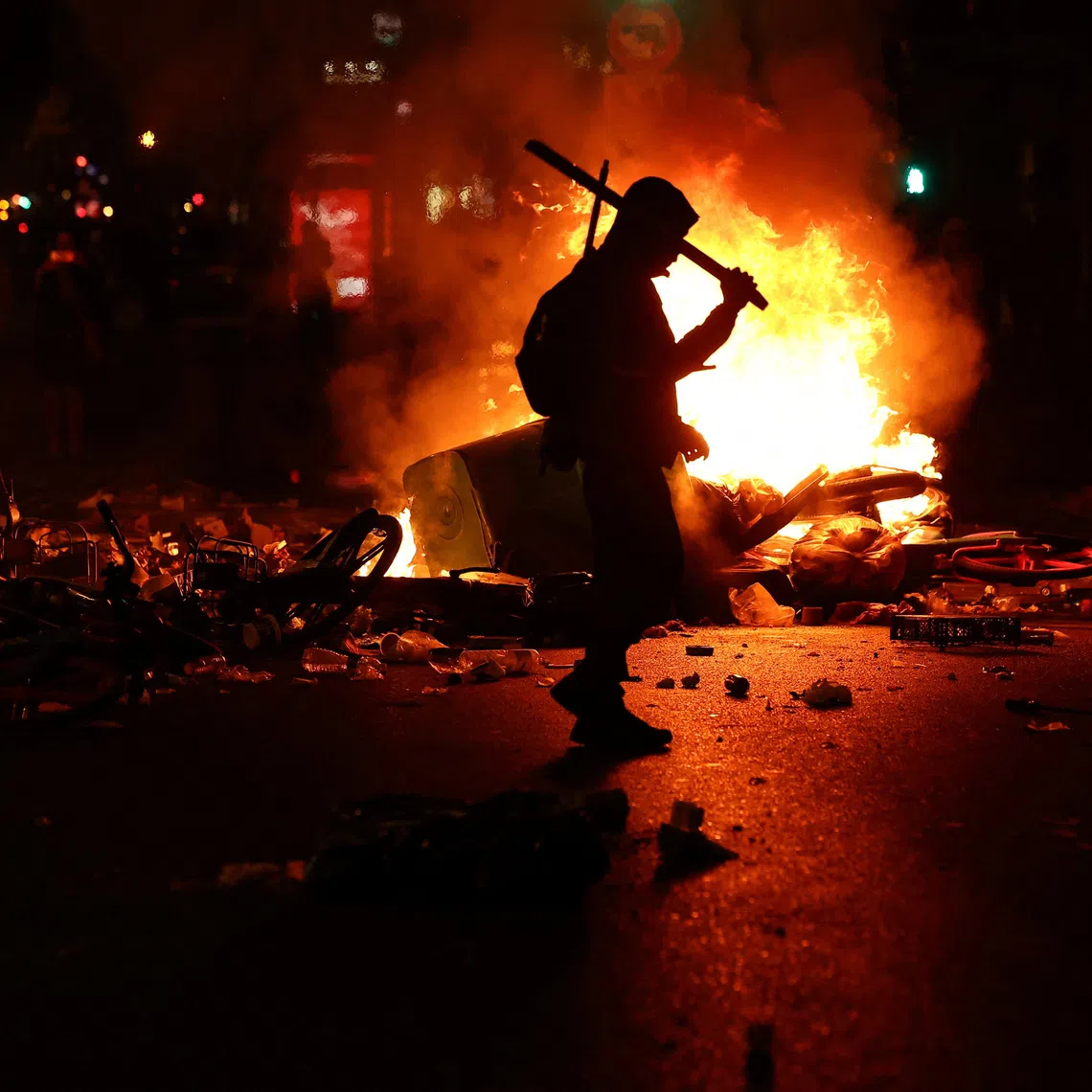 A person walks as flames rise during civil unrest, the day after a national day of demonstrations against the cost of living and rising fuel prices, in Paris, France, on Oct 18.