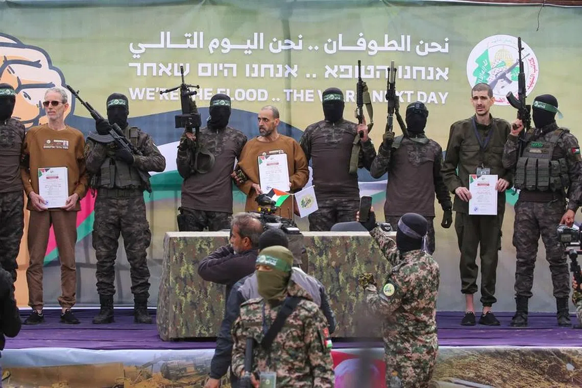 Hamas militants handing over (from left, holding certificates) Israeli hostages Ohad Ben Ami, Eli Sharabi and Or Levy to a Red Cross team in Gaza on Feb 8.