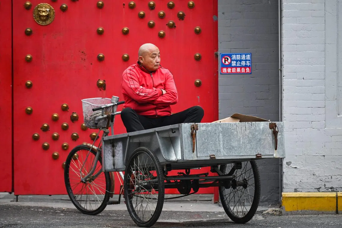 A man waits on the back of a delivery tricycle in Beijing on May 5, 2025. Apart from the hit to sentiment, tariffs have also led to the slowest rise in new business orders since December 2022. 
