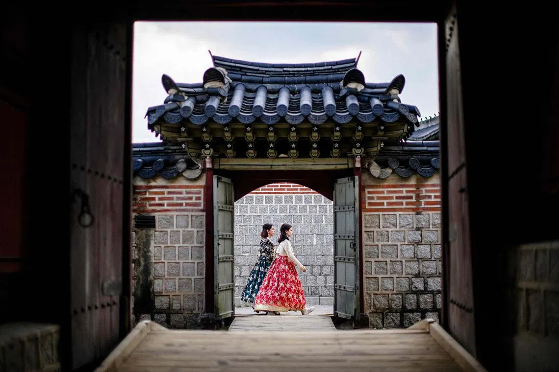 TOPSHOT - Women wearing traditional hanbok dresses visit the Gyeongbokgung Palace in Seoul on August 19, 2024. (Photo by Anthony WALLACE / AFP)