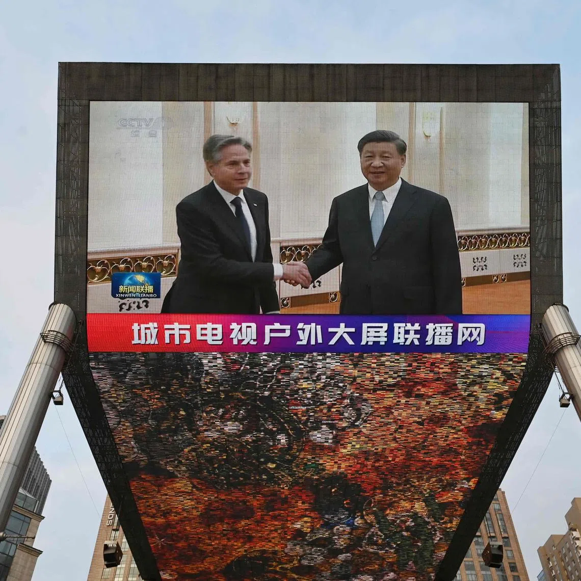 TOPSHOT - A China Central Television news broadcast shows footage of US Secretary of State Antony Blinken (L) meeting with China's President Xi Jinping, on a giant screen outside a shopping mall in Beijing on June 19, 2023. (Photo by GREG BAKER / AFP)