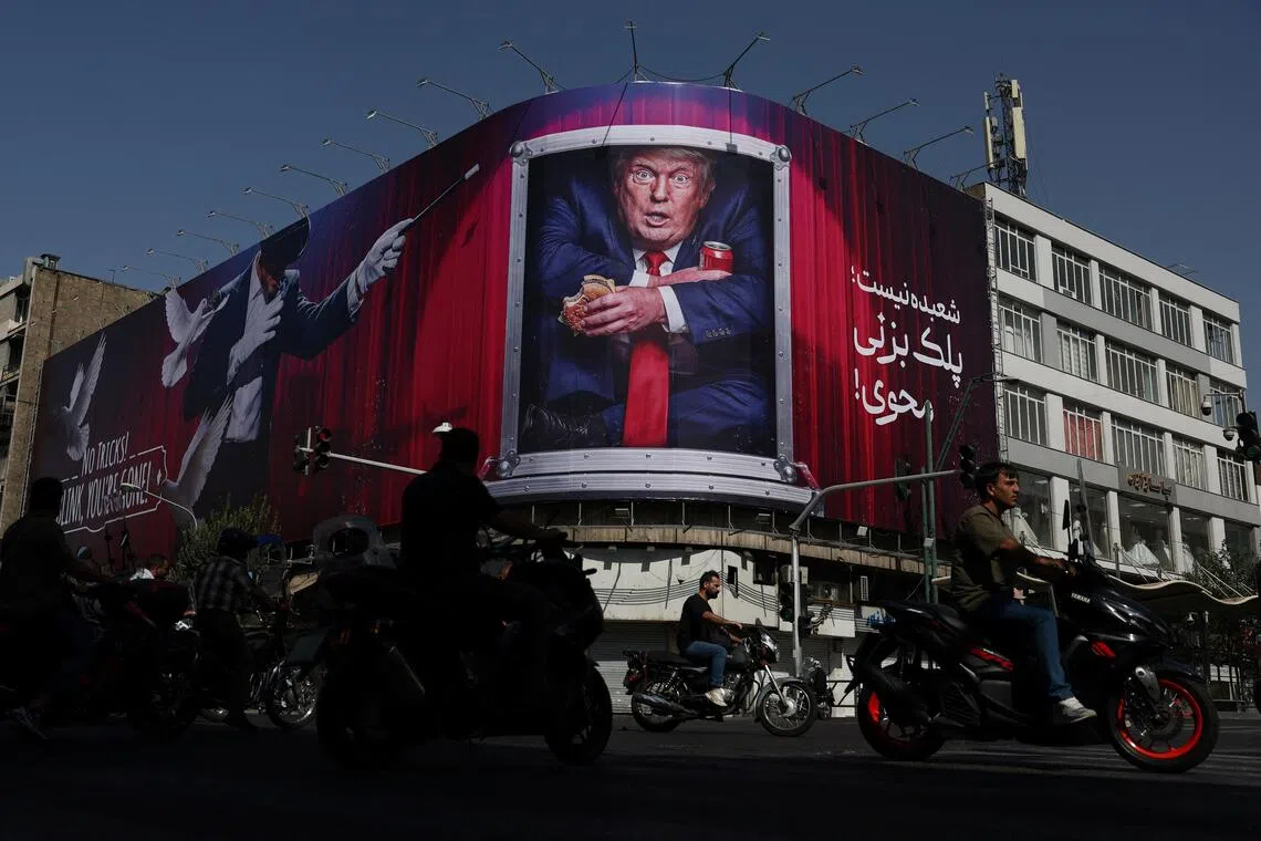 People drive near a billboard depicting US President Donald Trump on a building in Tehran.
