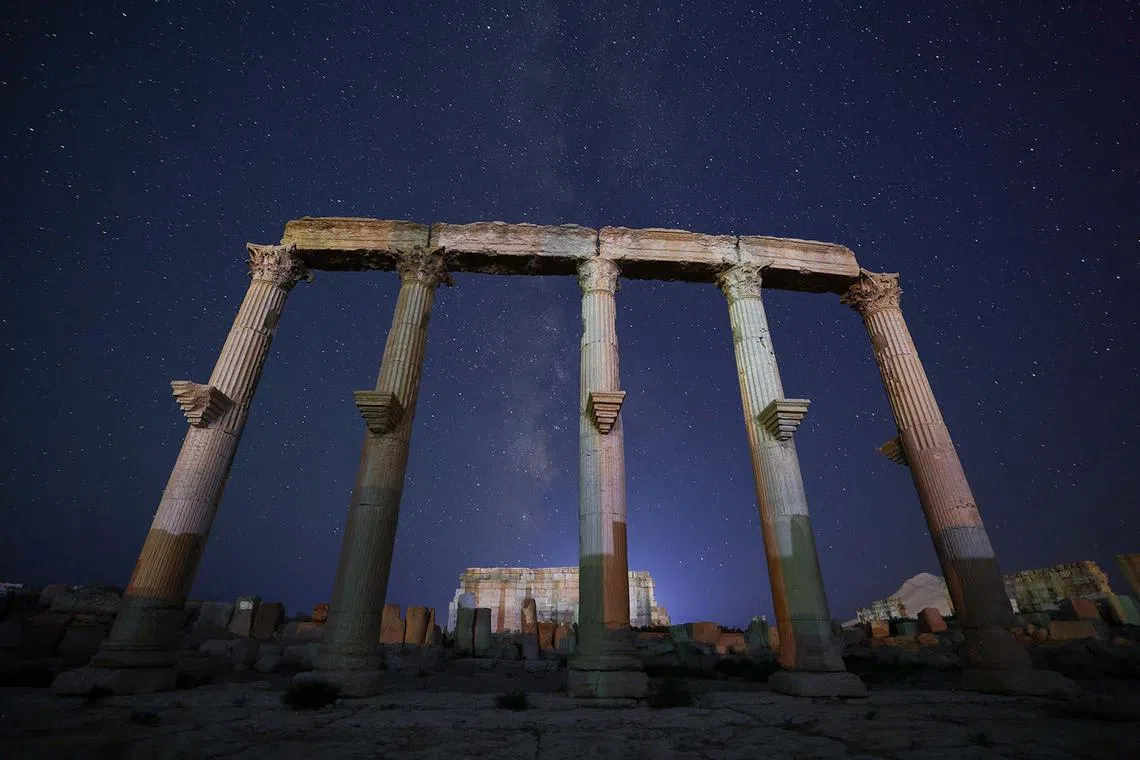 TOPSHOT - The Milky Way’s galactic center is seen above the ancient ruins of Palmyra in central Syria on August 23, 2025. Palmyra is one of six Syrian sites inscribed on UNESCO’s World Heritage list, all of which suffered varying degrees of damage during the country’s 13-year civil war. During their occupation of the site starting in 2015, jihadists from the Islamic State (IS) group destroyed several temples, columns, and other ancient treasures, reducing much of the city to rubble. (Photo by OMAR HAJ KADOUR / AFP)
