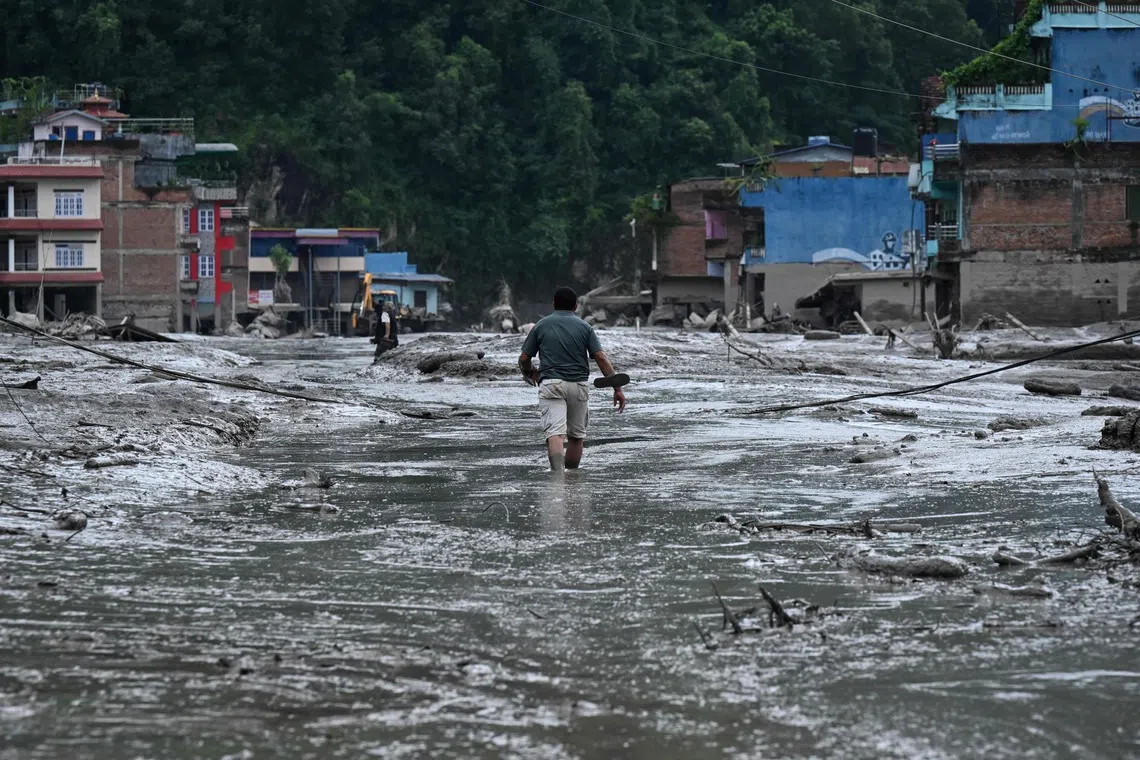 A resident walks along a street covered in mud following flash floods and a landslide disaster in Devghat, in Nepal’s Nuwakot district on Aug 26.