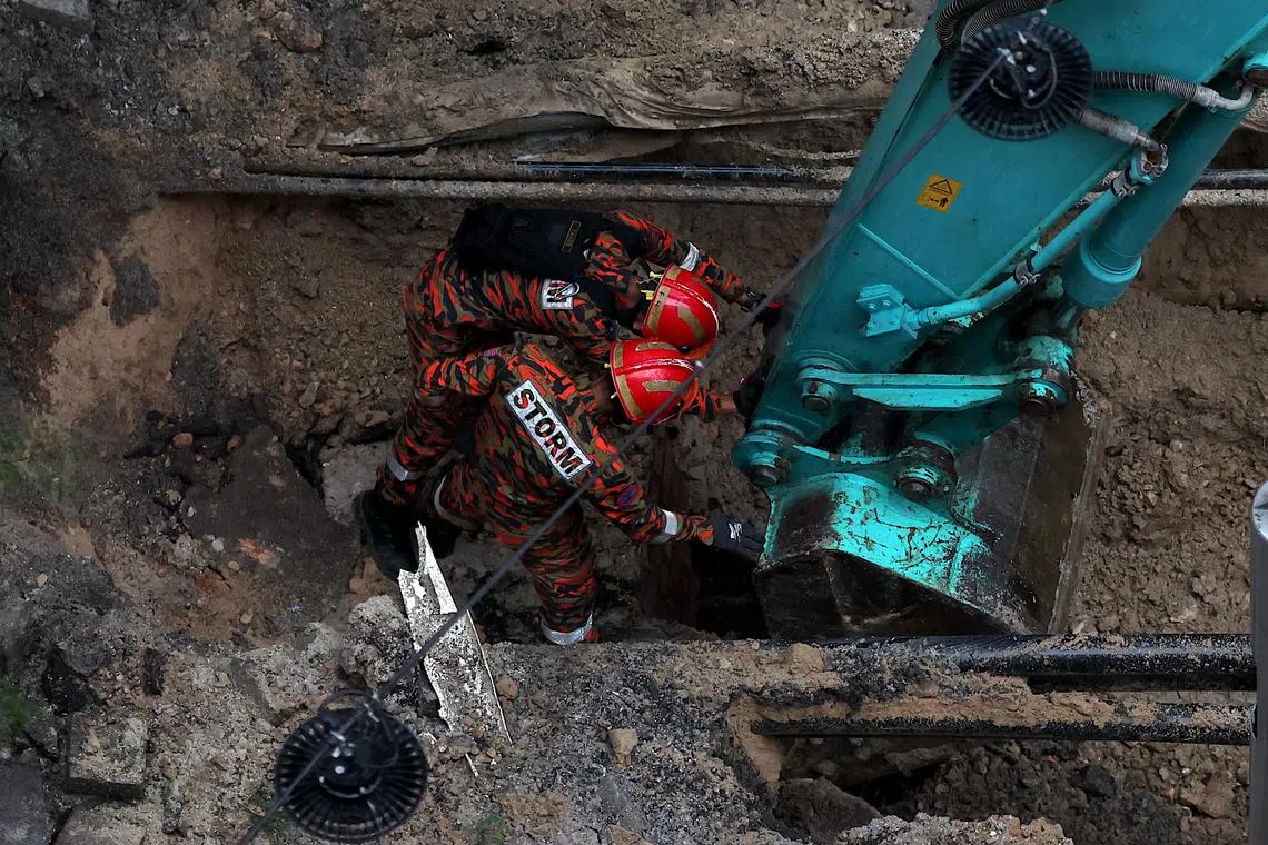 Malaysia Fire and Rescue Department officers inspect the site where a woman fell into a sinkhole on Jalan Masjid India in Kuala Lumpur, on Aug 23.