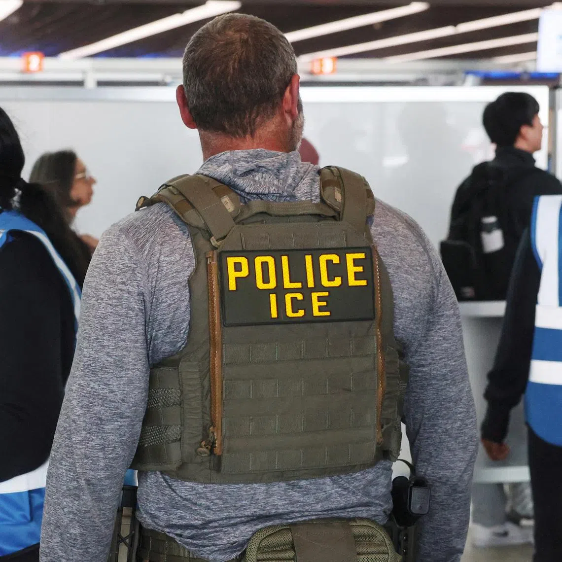 An Immigration and Customs Enforcement (ICE) agent stands while air travellers wait in TSA Security lines at John F. Kennedy International Airport, Queens, New York City, U.S., March 27, 2026. REUTERS/Shannon Stapleton