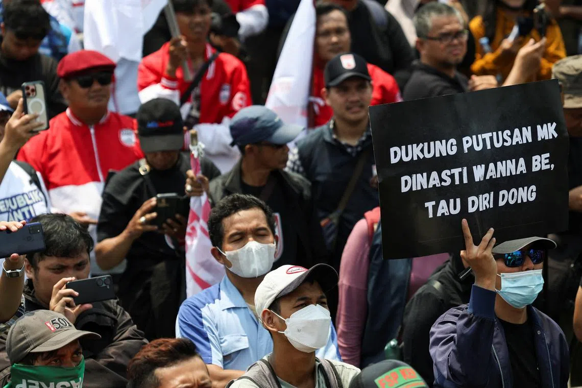 A man carries a placard that reads \"In the Constitutional Court's ruling on the wannabe dynasty, know your place\" during a protest outside the Indonesian Parliament against the revisions to the country's election law, which analysts believe goes through a rushed process of legislation and is designed to block a popular candidate from running as the capital's governor in Jakarta, Indonesia, August 22, 2024. REUTERS/Ajeng Dinar Ulfiana