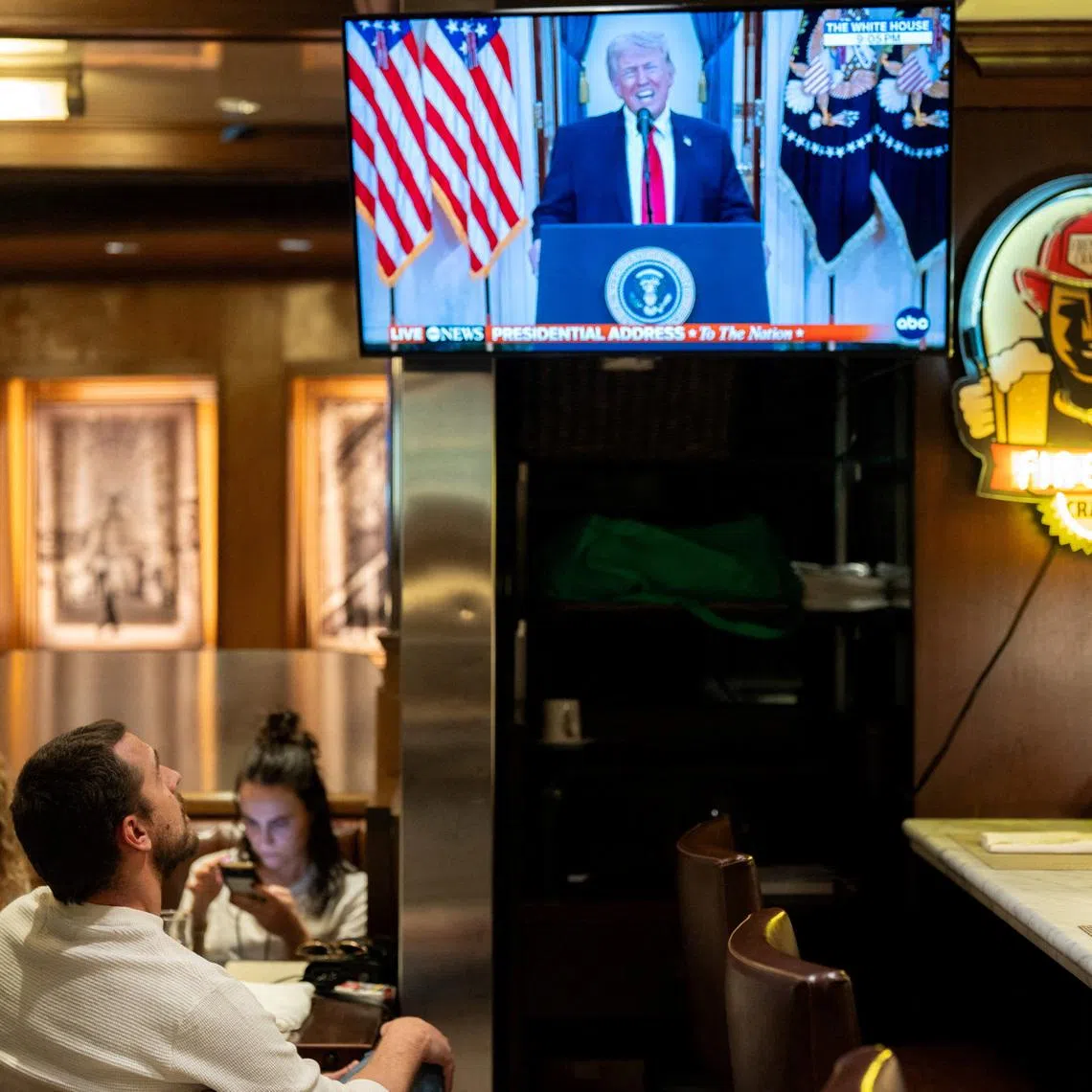 A customer watches U.S. President Donald Trump address the nation on the Iran crisis from the White House in Washington, D.C., on screen at Brooklyn Diner in Times Square, New York, U.S., April 1, 2026. REUTERS/David Dee Delgado/File Photo