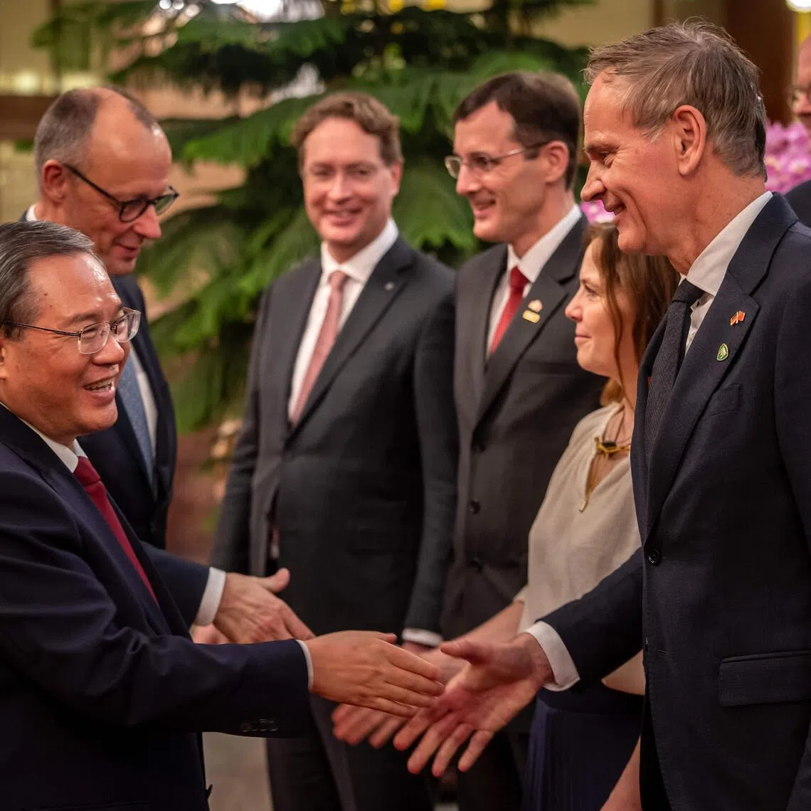 Chinese Premier Li Qiang greeting Volkswagen CEO Oliver Blume as he welcomed the business delegation that accompanied German Chancellor Friedrich Merz (left, behind Mr Li) at the Great Hall of the People in Beijing on Feb 25.