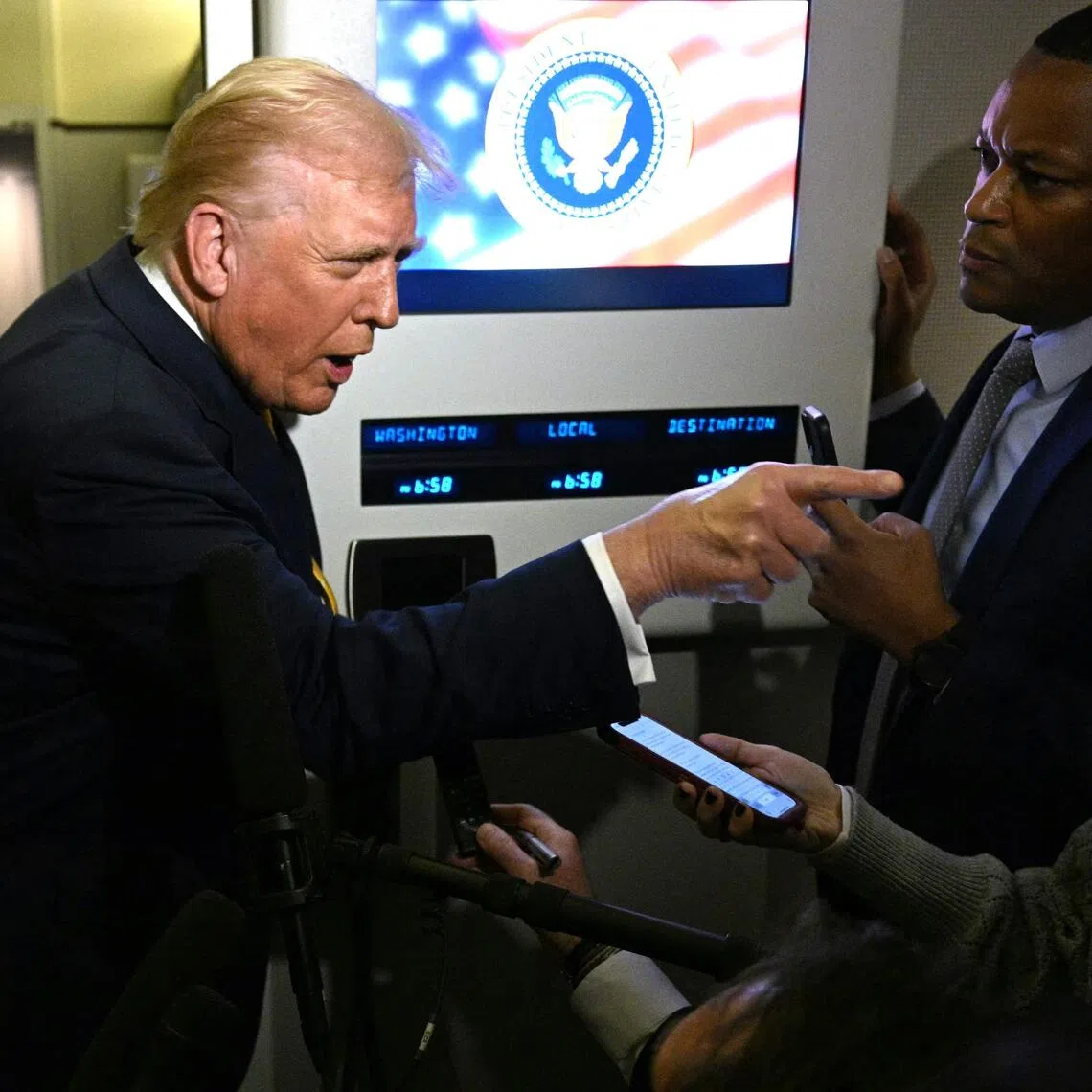 US President Donald Trump points as he speaks to reporters aboard Air Force One en route to Palm Beach, Florida, on Nov 14, 2025.