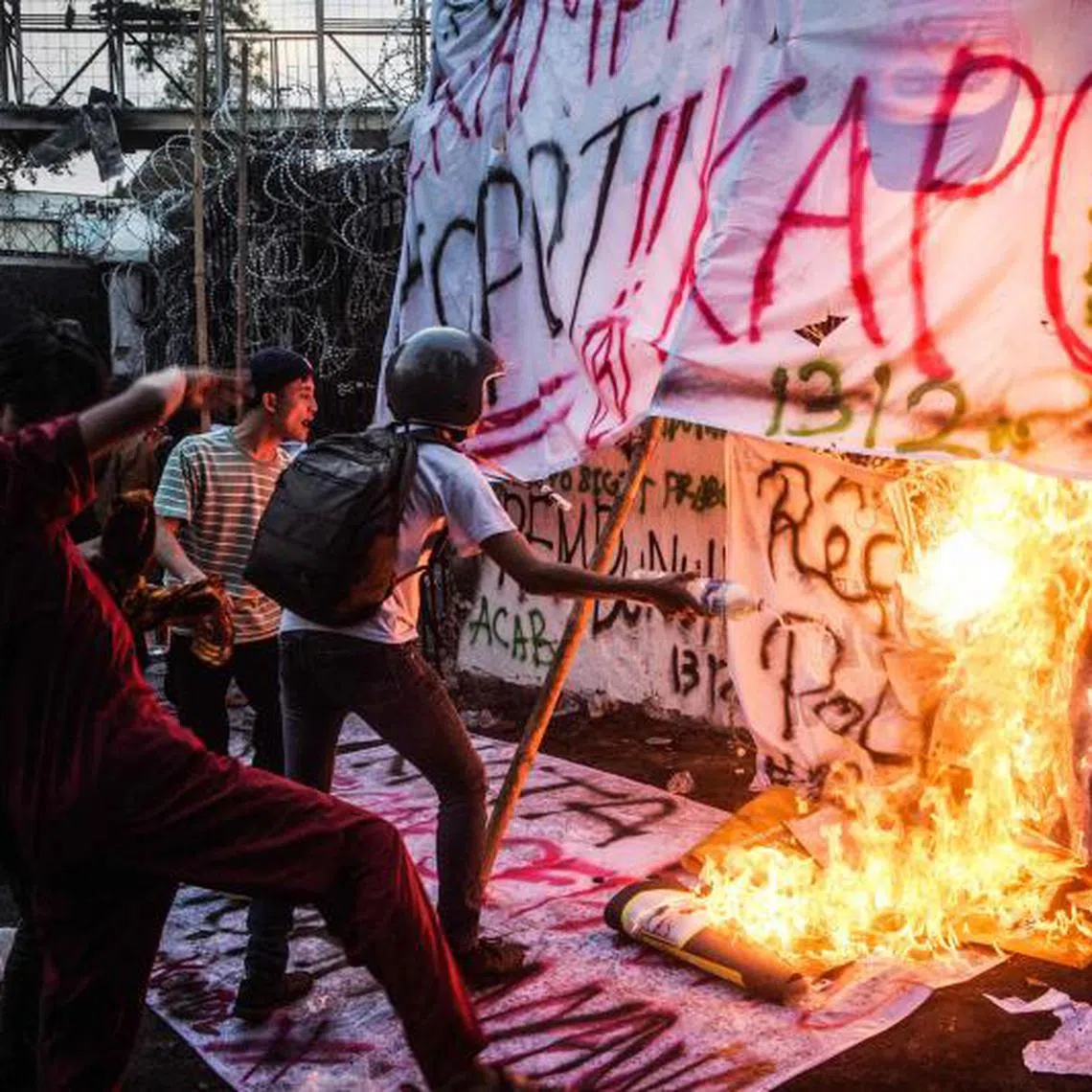 Protesters set alight banners as they shout slogans demanding police reform and the dissolution of the Parliament in Bandung, West Java.