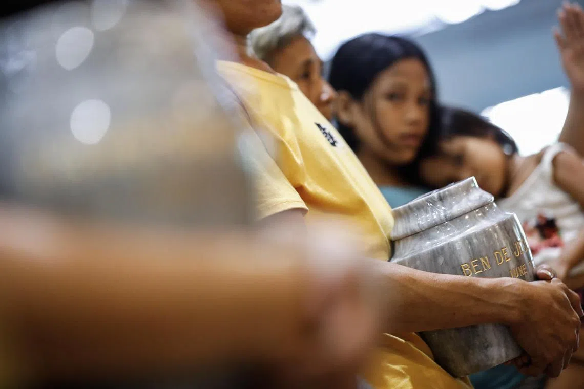 A woman holds an urn containing the remains of one of the thousands killed in former Philippine president Rodrigo Duterte's brutal drug war.