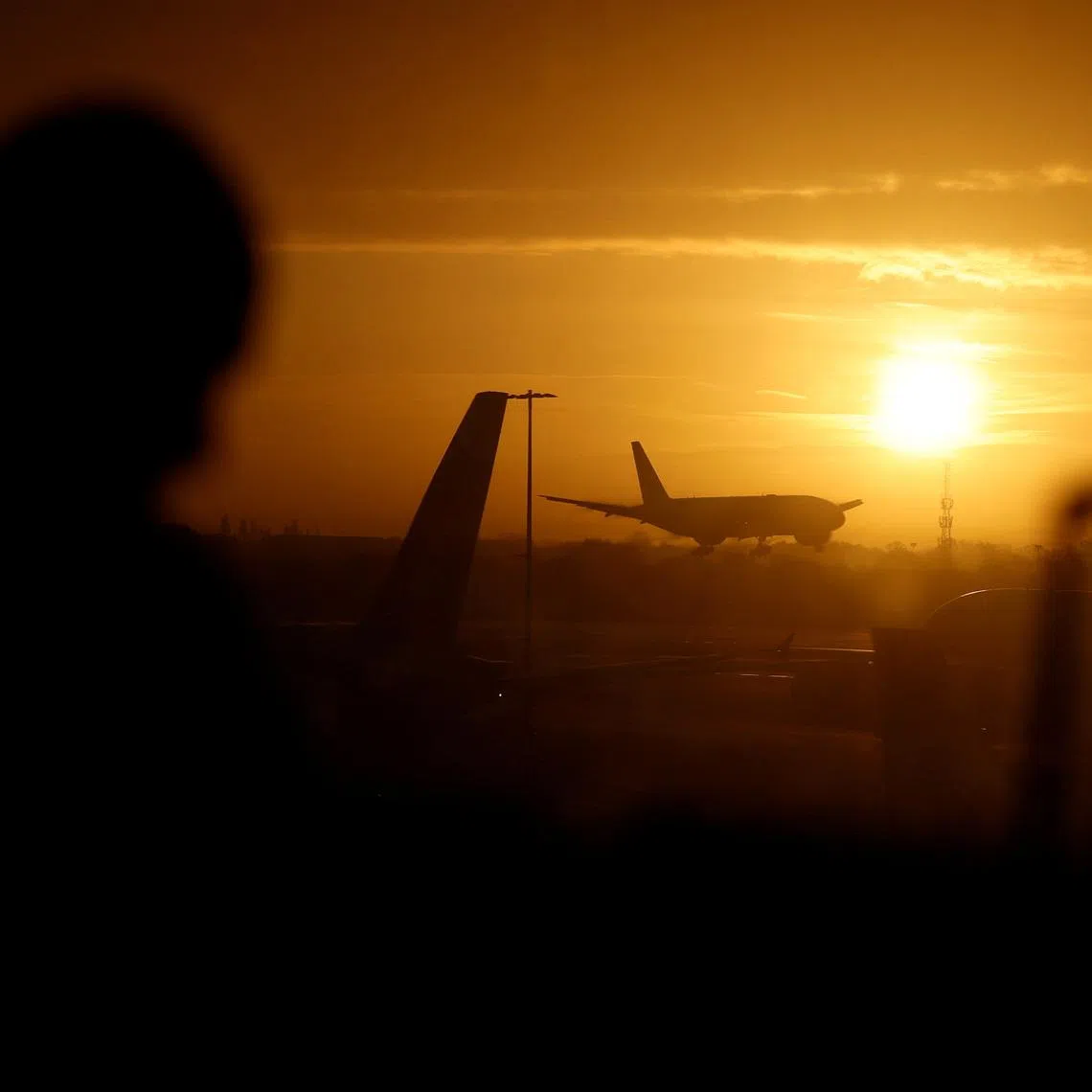 A passenger waits in departures as a British Airways plane lands at London Heathrow airport, London, Britain, November 15, 2025. REUTERS/Peter Cziborra/File Photo