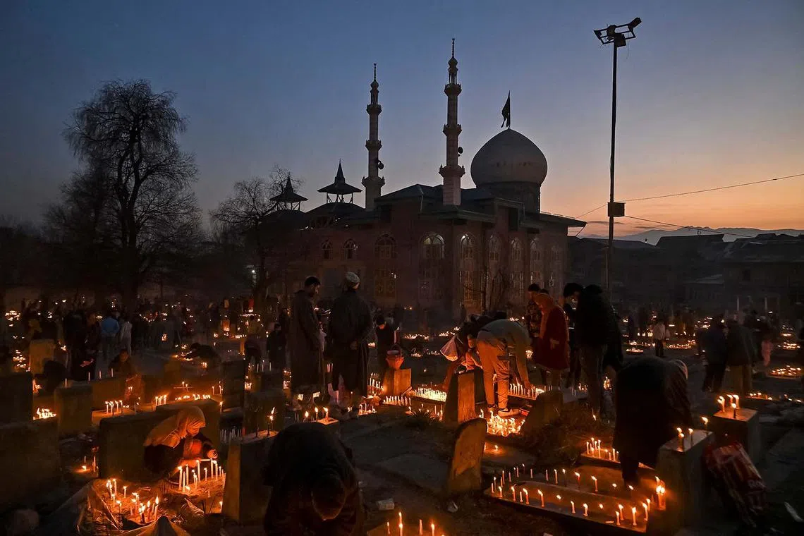 Kashmiri Shiite Muslims offering prayers as they light candles at the graves of their relatives to mark Shab-e-Barat, or the night of forgiveness, at a graveyard in Srinagar on Feb 13, 2025. 