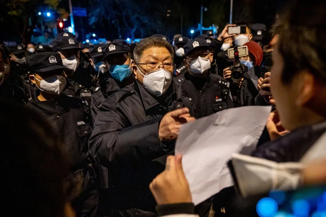 A local official speaks with a demonstrator holding a blank sign during a protest in Beijing, China, Nov 28, 2022. Protests against Covid restrictions spread across China on Sunday as citizens took to the streets and university campuses, venting their anger and frustrations on local officials and the Communist Party. 