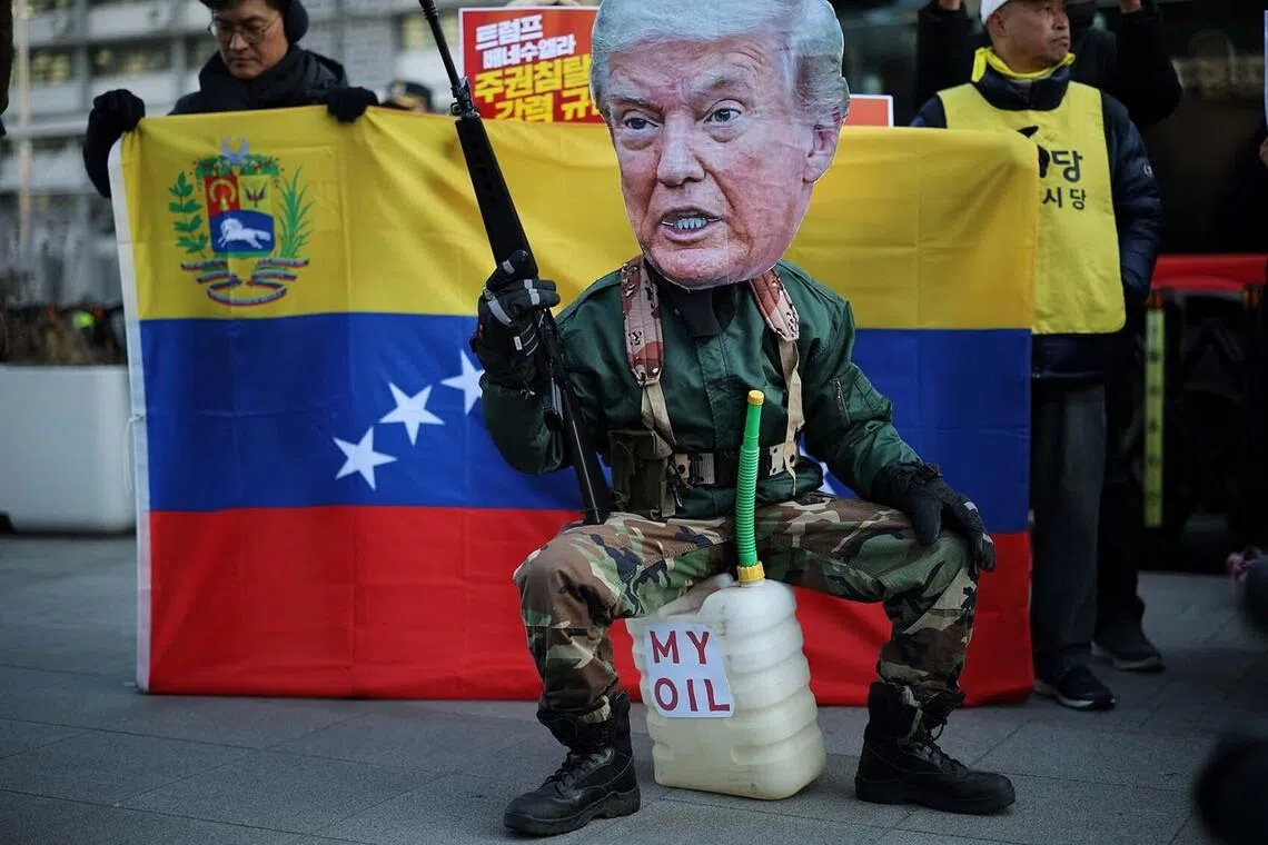 An activist, wearing a cutout mask depicting U.S. President Donald Trump, holds a toy gun and sits on a container with the words, "My Oil" during an anti-Trump rally to condemn the U.S. conducting a military act on Venezuela to capture its President Nicolas Maduro and his wife Cilia Flores, in central Seoul, South Korea, January 5, 2026. REUTERS/Kim Hong-Ji