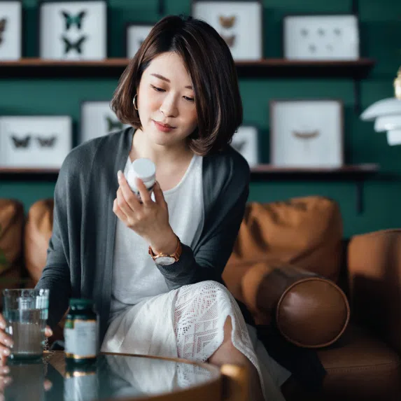 Best probiotics for women in Singapore: Asian woman reading labels on a bottle