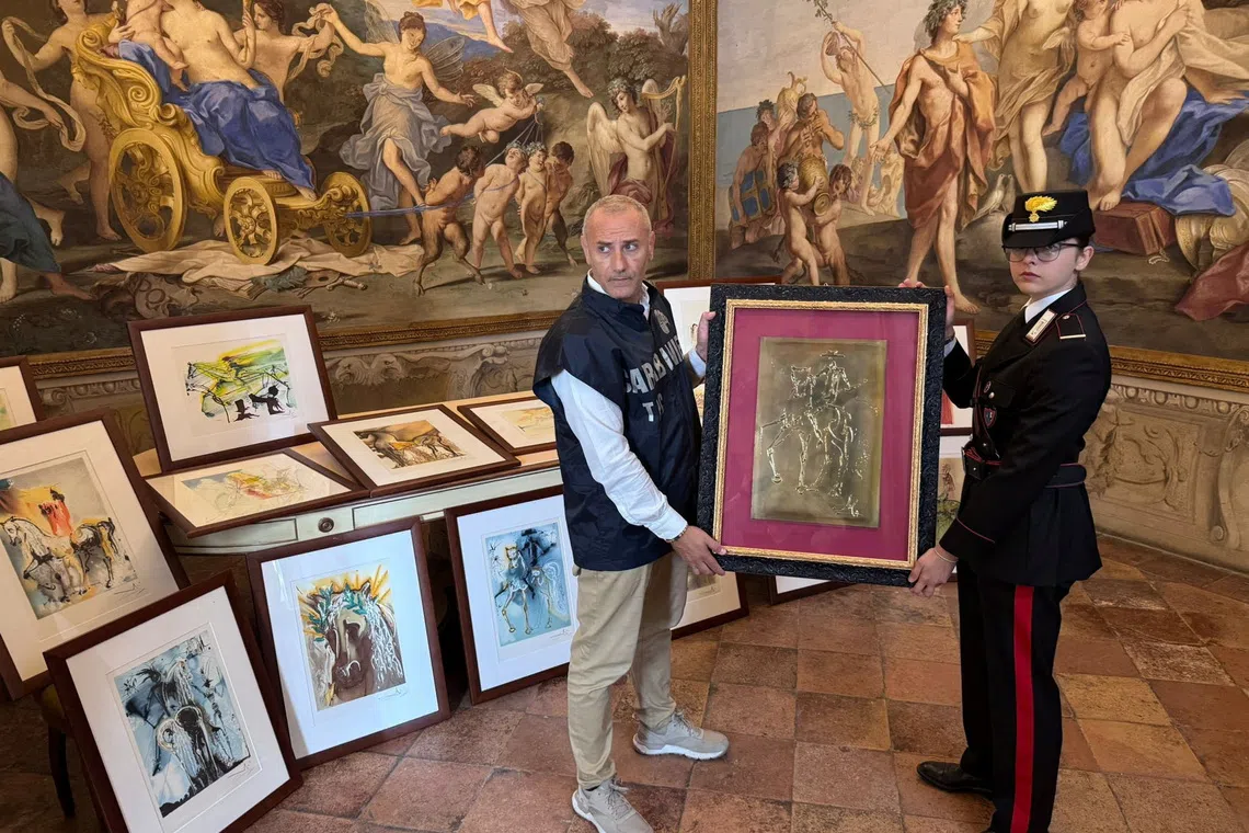 Carabinieri officers hold one of the 21 artworks presumed to be inauthentic and falsely attributed to Salvador Dali, seized during an exhibition in Parma following an investigation by the Rome Public Prosecutor's Office, in Rome, Italy, in this handout picture obtained on October 1, 2025. Carabinieri/Handout via REUTERS    THIS IMAGE HAS BEEN SUPPLIED BY A THIRD PARTY
