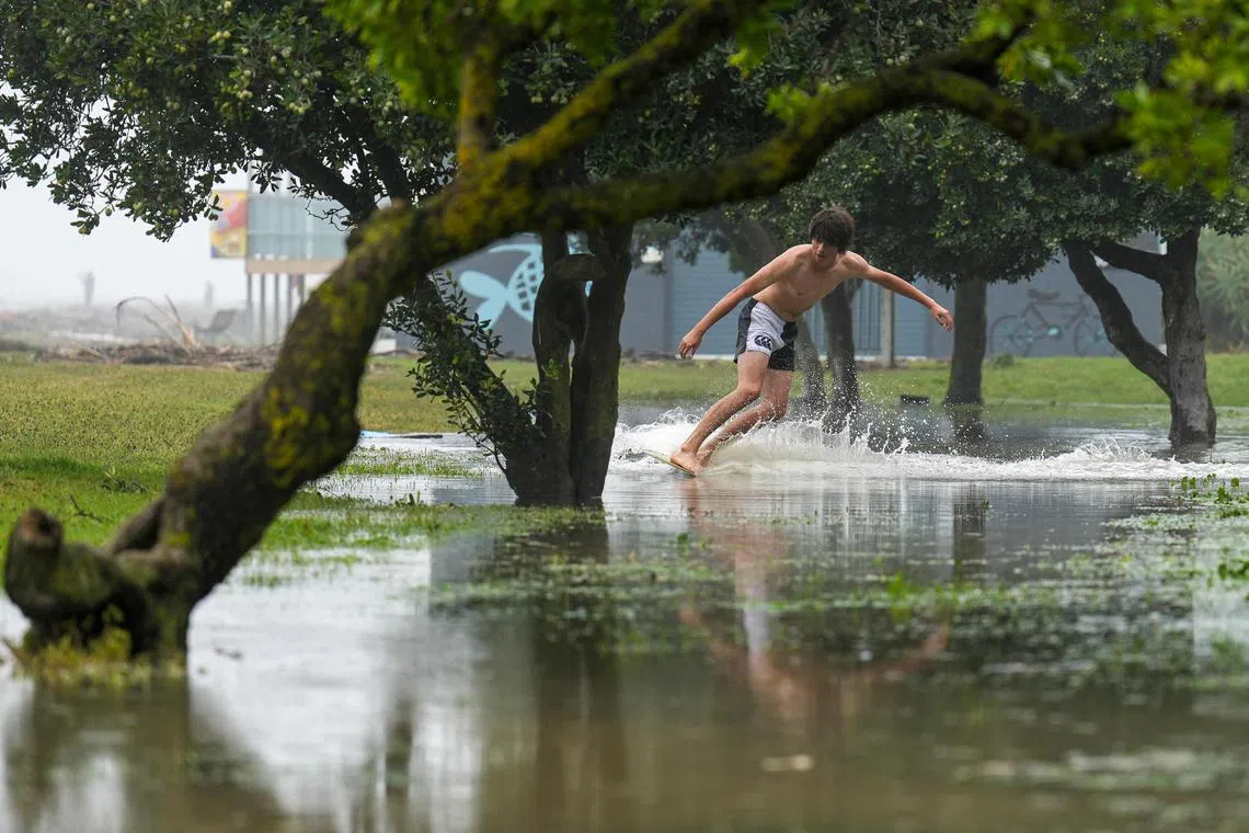 A boy is seen skimming on floodwaters along Marine Parade in the North Island city of Napier, Feb 14, 2023. 