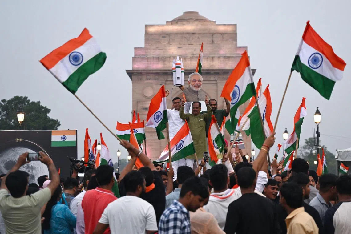 People wave India's national flags as they celebrate the successful lunar landing of Chandrayaan-3 spacecraft on the south pole of the Moon, in New Delhi, on Aug 23.