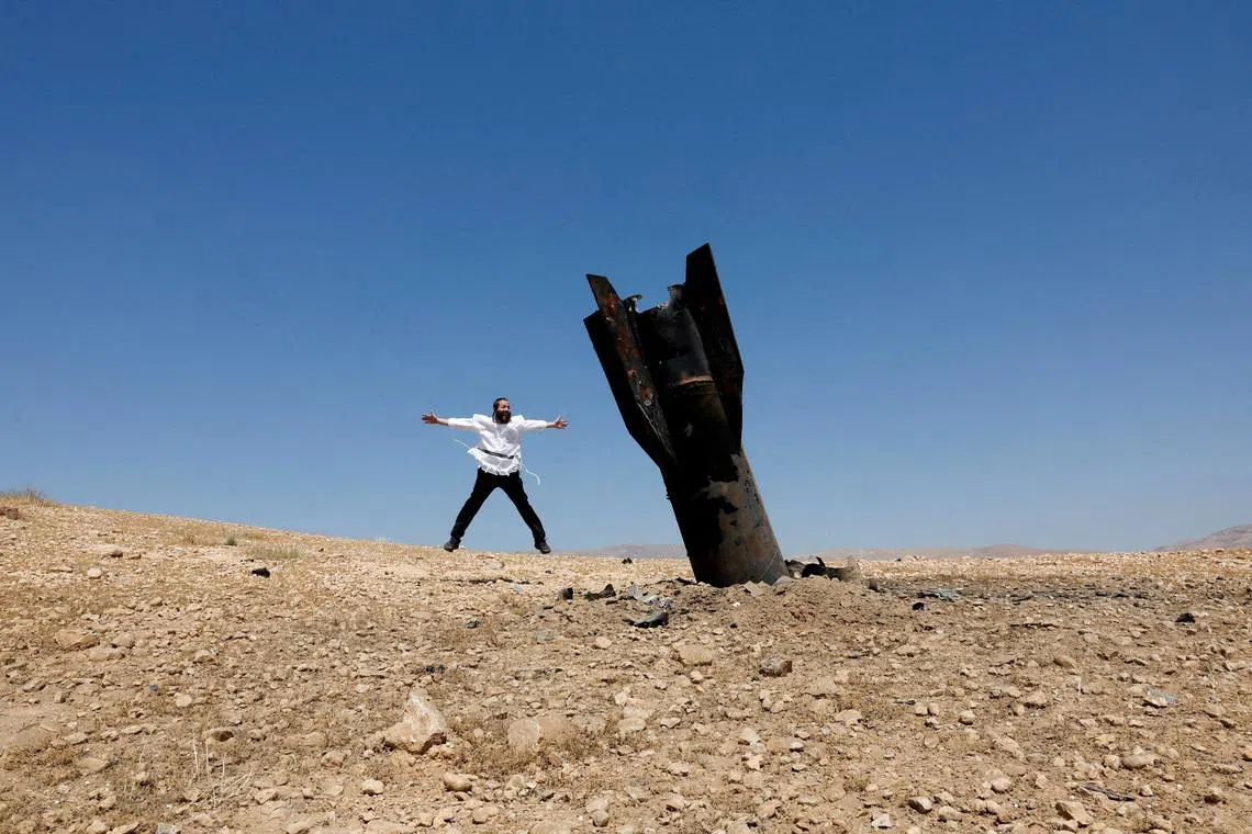 An Israeli ultra-Orthodox Jewish man near a part of a missile protruding from the ground, following strikes from Iran, in the central Israeli-occupied West Bank, on June 8, 2026. 