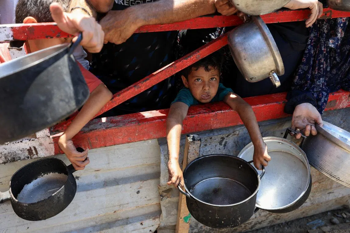 A child holds a pot as Palestinians gather to receive food from a charity kitchen, amid a hunger crisis, in Gaza City, July 22, 2025. REUTERS/Dawoud Abu Alkas