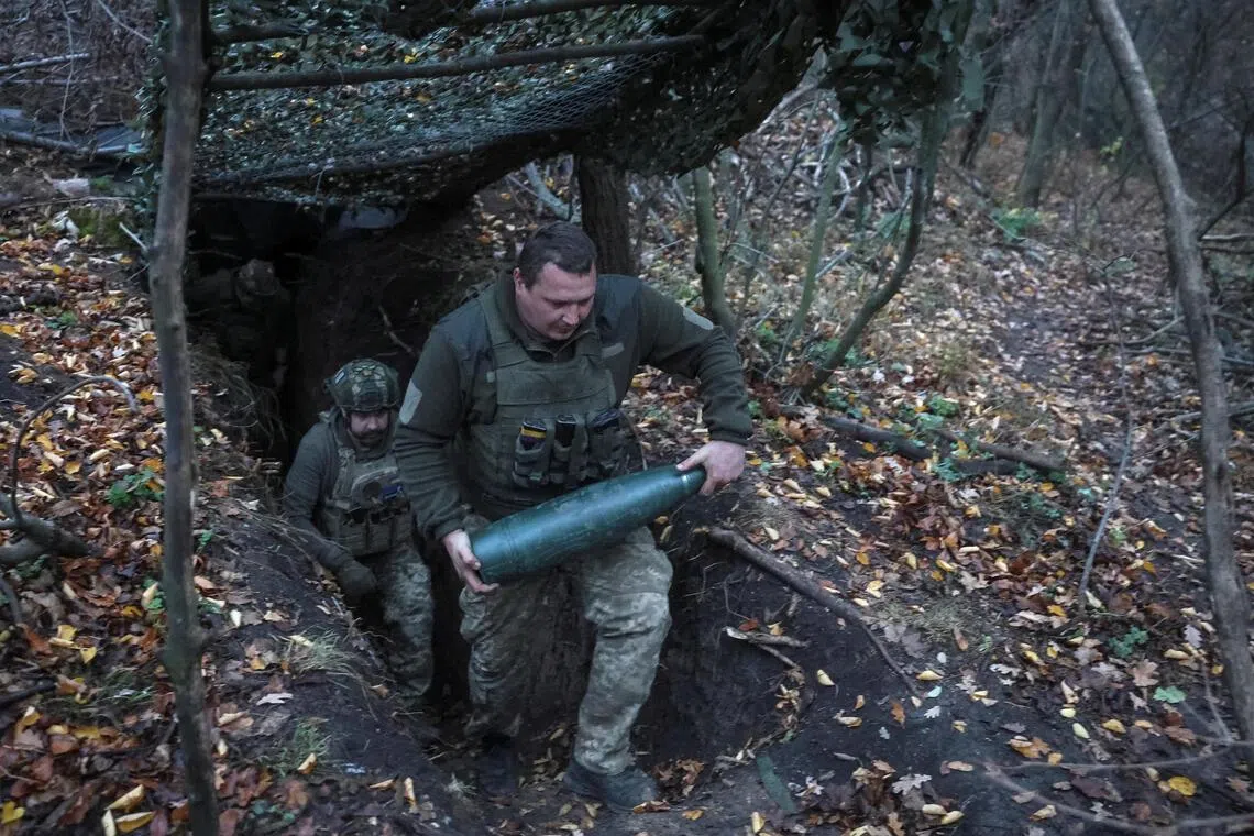A Ukrainian serviceman carries a shell for a self-propelled howitzer, as he prepares to fire towards Russian troops near the front line in Ukraine's Donetsk region.