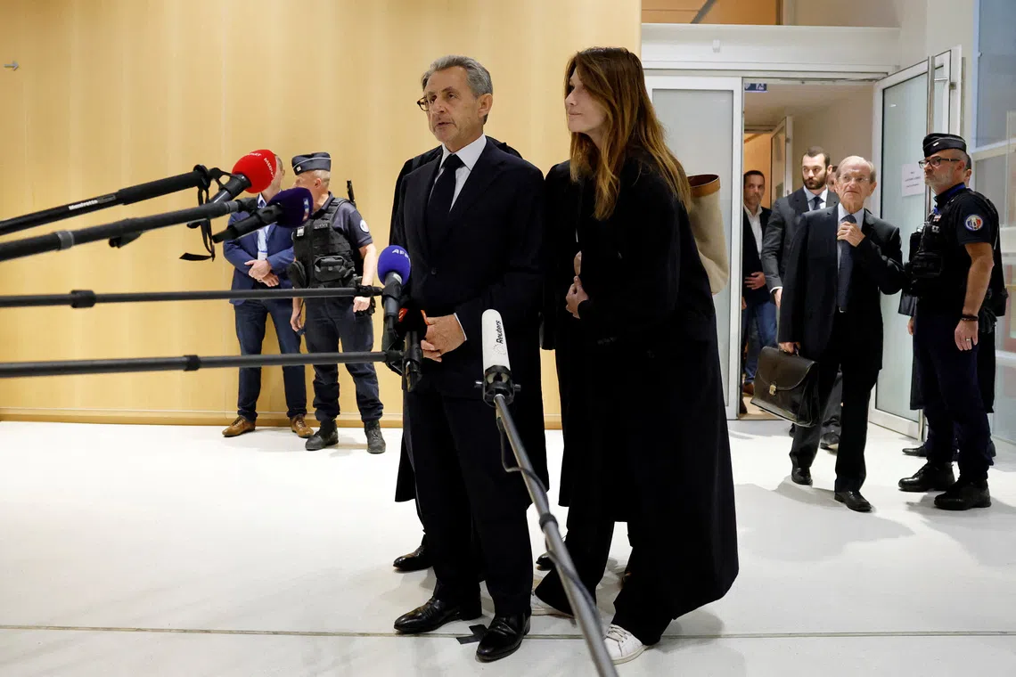 Former French president Nicolas Sarkozy talking to journalists at a court in Paris on Sept 25, with wife Carla-Bruni Sarkozy.