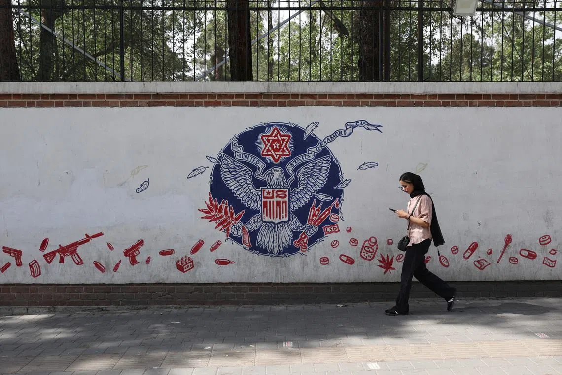 A woman walks past an anti-US mural on a street in Tehran, Iran, June 5, 2025. Majid Asgaripour/WANA (West Asia News Agency) via REUTERS