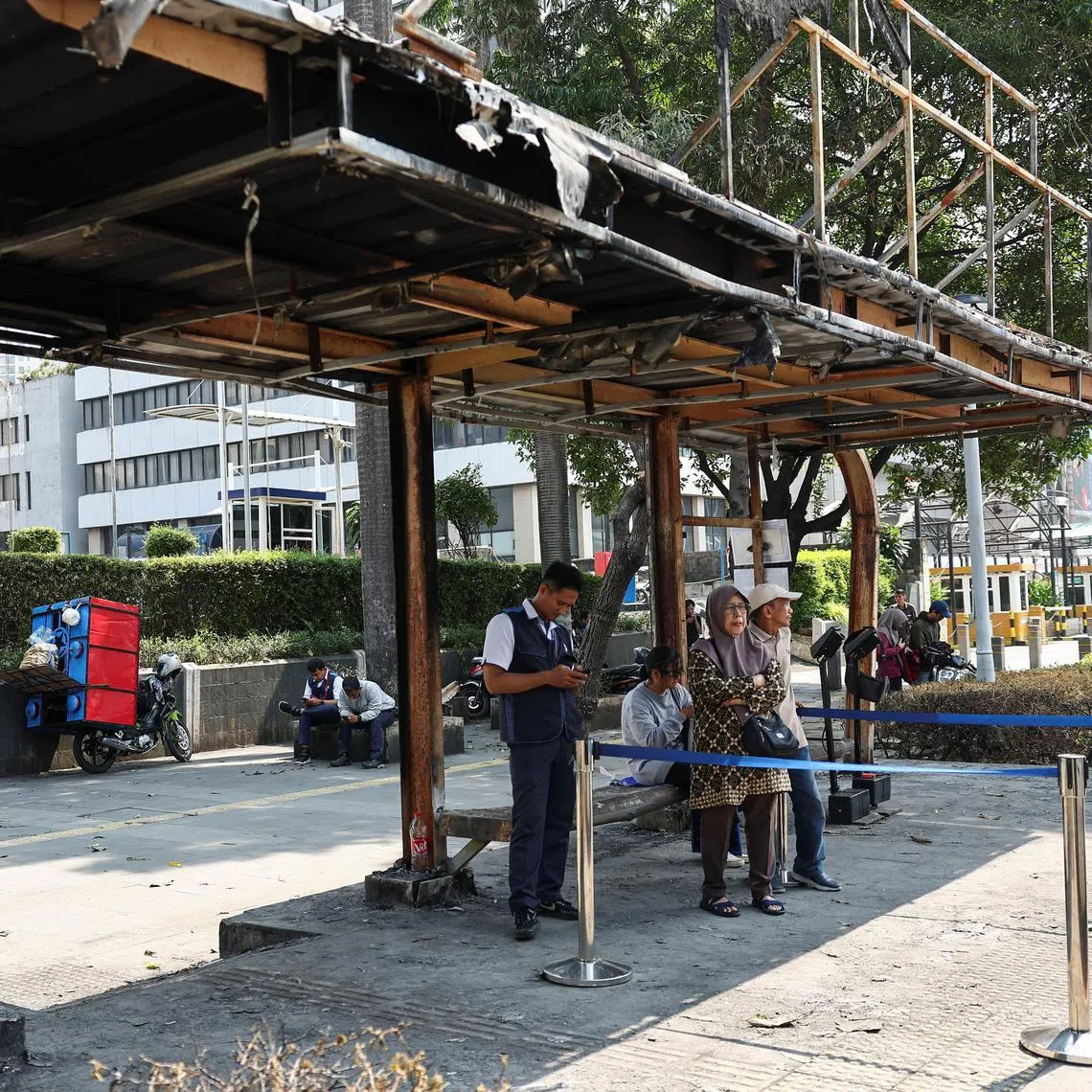 Commuters at a burnt bus stop following a recent protest against police violence, in Jakarta, Indonesia, on Sept 2.