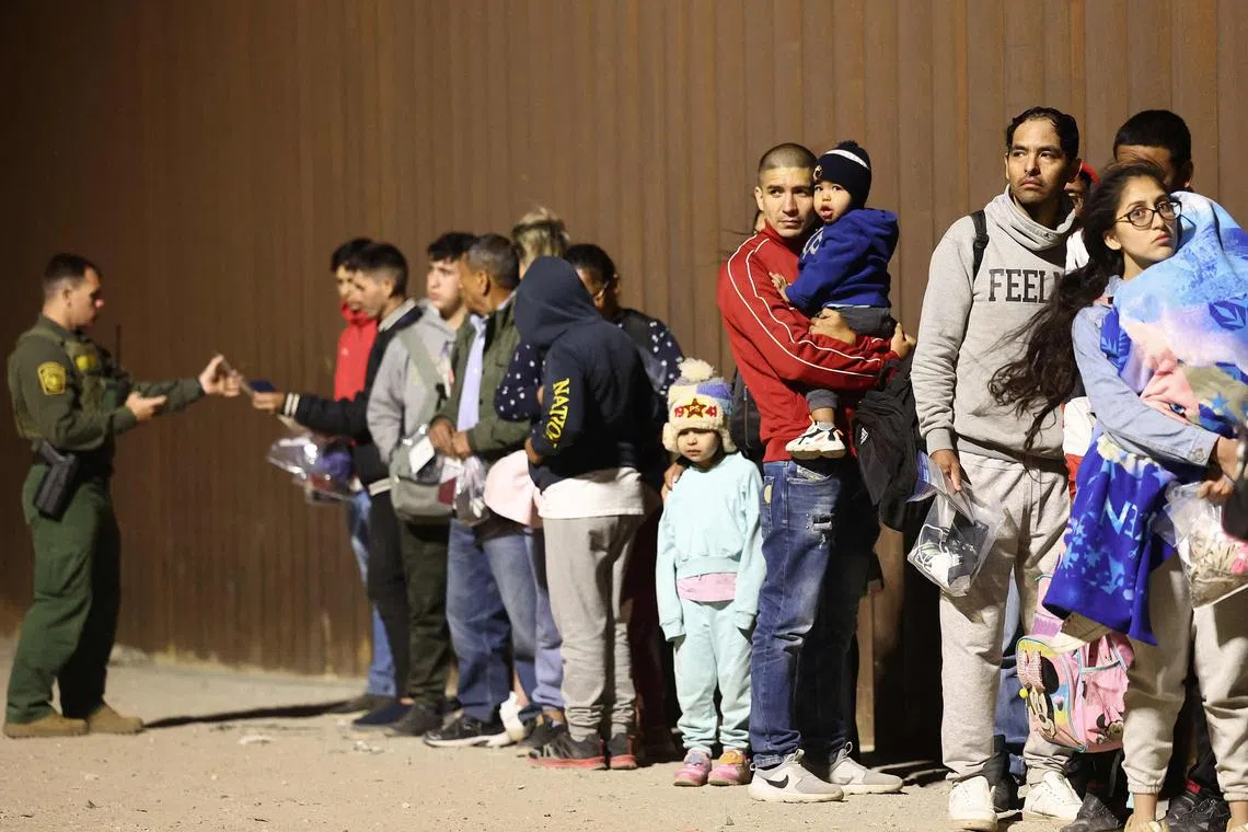 Immigrants seeking asylum in the US stand in line for processing by Border Patrol agents after crossing into Arizona from Mexico. 