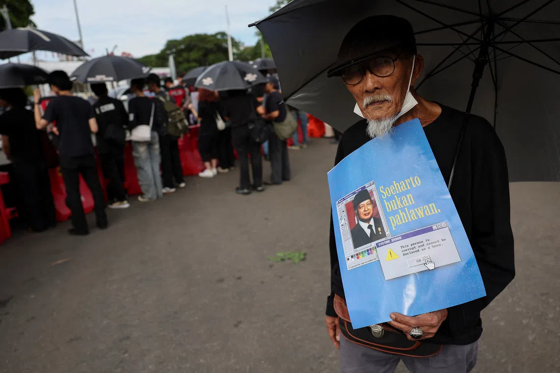 Effendi Saleh, 87, who says that he was detained for 10 years during the late President Suharto’s era, holds a placard during a protest against government's plans to name Suharto a national hero, outside the Presidential Palace in Jakarta, Indonesia, November 6, 2025. REUTERS/Willy Kurniawan