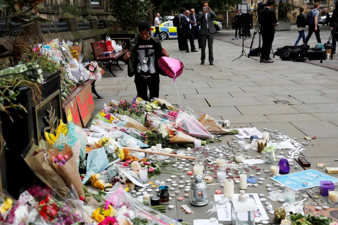 FILE PHOTO: An Ariana Grande fan stands next to floral tributes left for the victims of an attack on concert goers at Manchester Arena, in St Ann's Square, in Manchester, Britain May 24, 2017. REUTERS/Darren Staples/File Photo