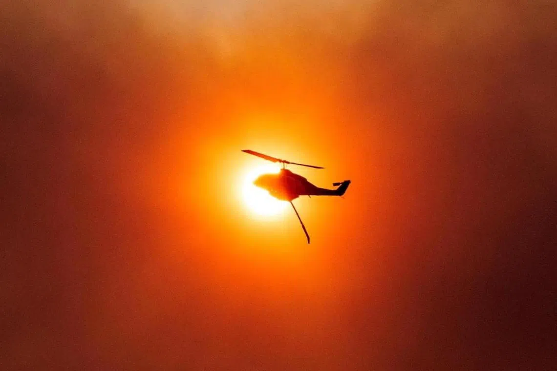 A firefighting helicopter silhouetted against of the sun as a wildfire burns in the suburb of Mandra, Greece, on July 18, 2023.