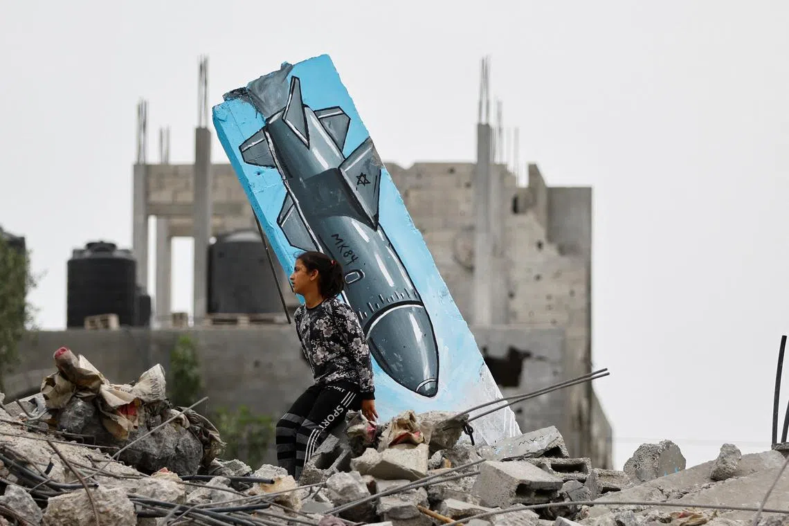 A Palestinian girl sitting on the remains of a destroyed house, next to a graffiti of a missile drawn by Hussein Abu Sadeq, on houses destroyed by Israel in recent Israeli-Gaza fighting, in Deir Al-Balah, central Gaza Strip on June 8, 2023. 
