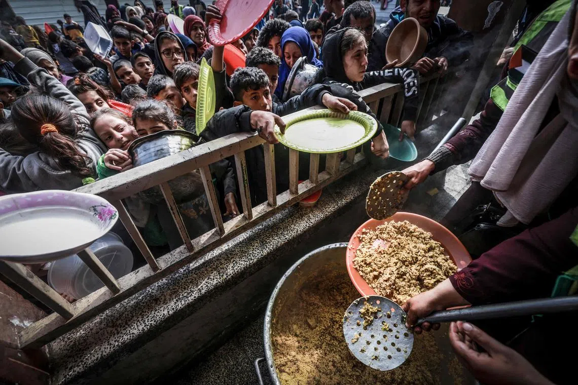 Displaced Palestinian children gather to receive food at a government school in Rafah on Feb 19.