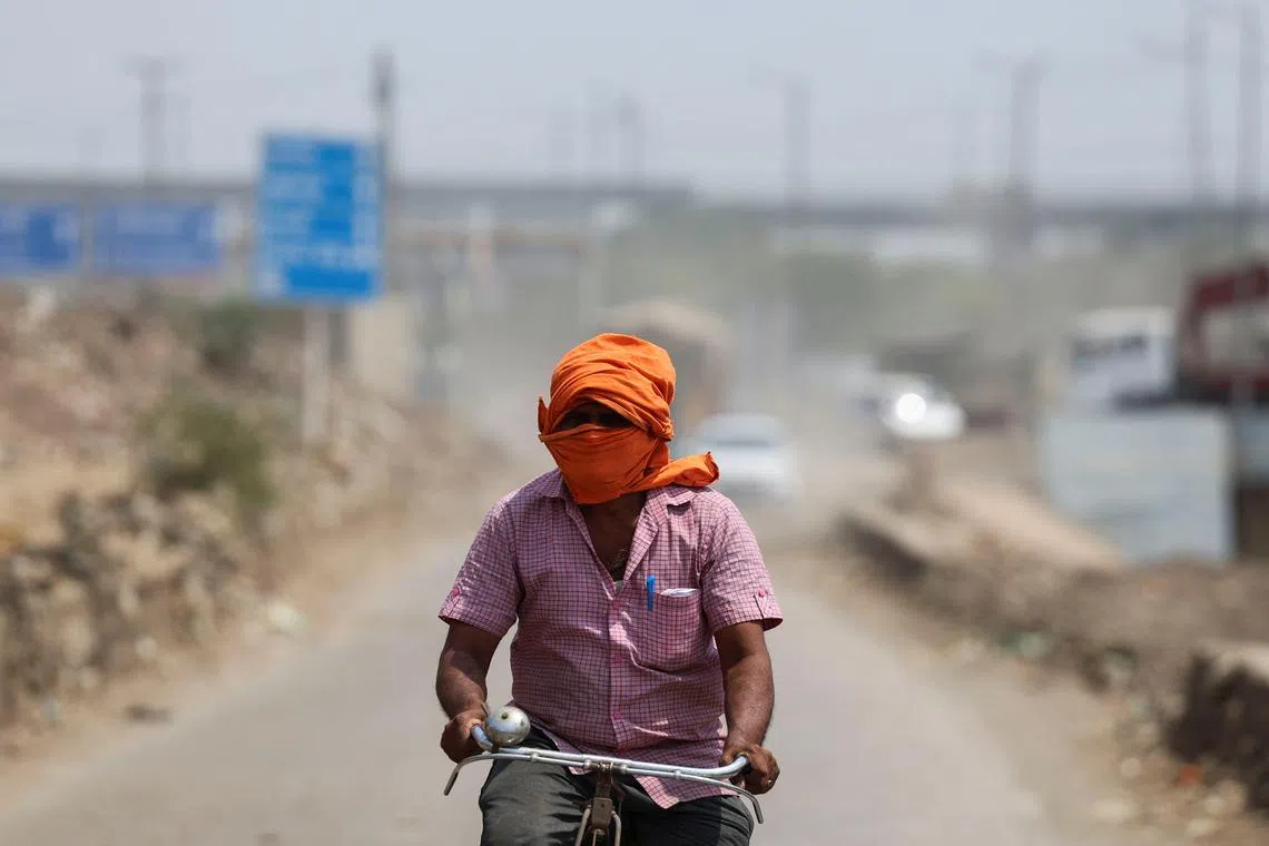 A man rides his cycle near a landfill site on a hot summer day during a heatwave in New Delhi, India, May 27, 2024. REUTERS/Anushree Fadnavis