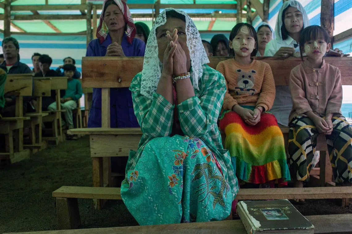 Children praying with their parents in a temporary church at a camp for internally displaced people (IDPs) in Demoso township in Myanmar's Kayah state