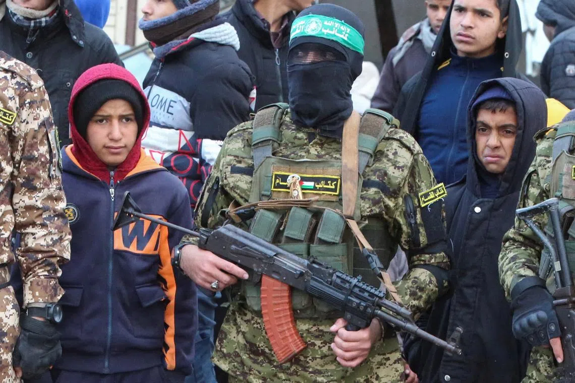 Palestinian Hamas militants stand guard as people gather on the day of the handover of hostages, including those held in Gaza since the deadly Oct 7, 2023 attack, to members of the International Committee of the Red Cross (ICRC) on Feb 22.