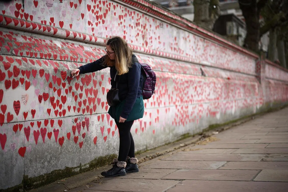 MEmily Payne adds a message on Britain's National Covid Memorial Wall, dedicated to her grandfather, who died from the disease.