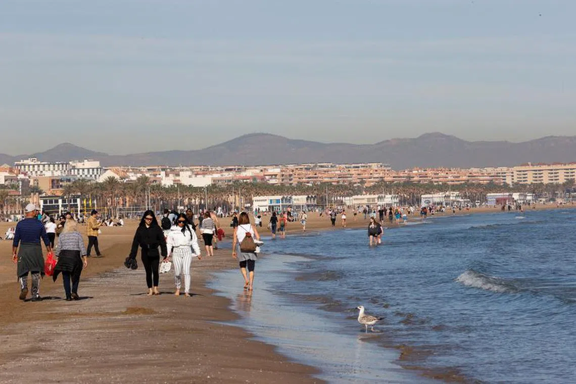 People walk along the seashore at the Malvarrosa beach in Valencia, Spain January 25, 2024 REUTERS/Eva Manez