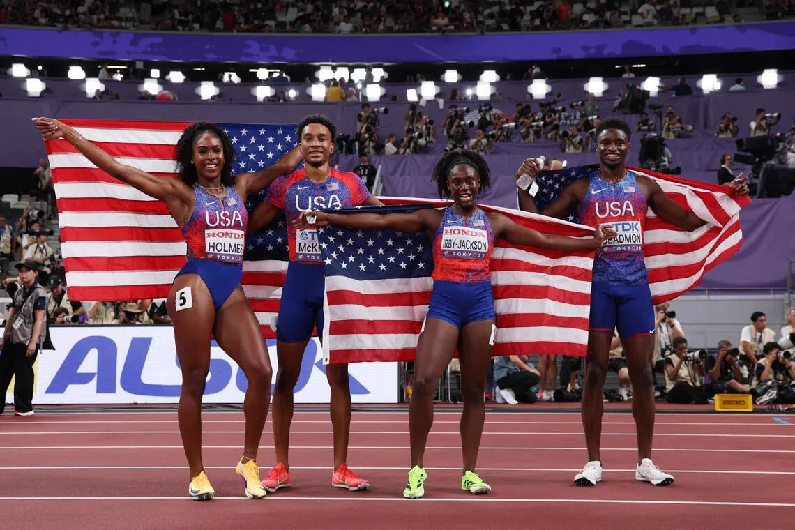 Bryce Deadmon, Lynna Irby-Jackson, Jenoah McKiver and Alexis Holmes celebrate with US flags after winning gold.