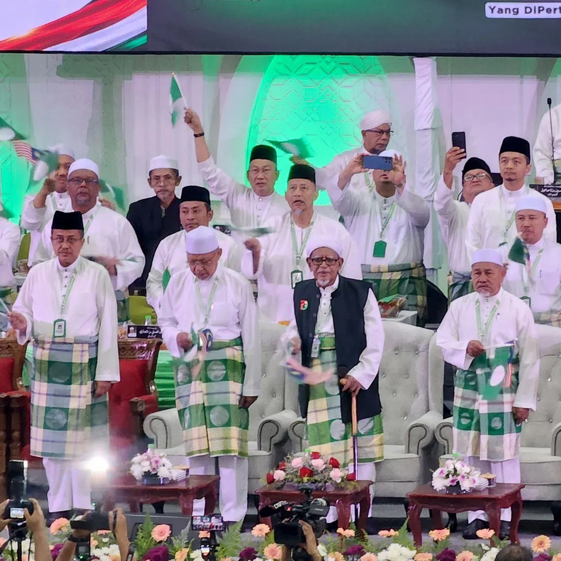 Malaysia’s opposition Parti Islam SeMalaysia (PAS) leaders gather on stage with UMNO secretary-general Asyraf Wajdi Dusuki (in red), at PAS’ annual party congress, or muktamar, in Pengkalan Chepa, near Kota Bharu, Kelantan, on Sept 4, 2026, as the rival Malay-based parties seek to strengthen their cooperation. Note: PAS president Hadi Awang is standing front, centre, in long black vest.