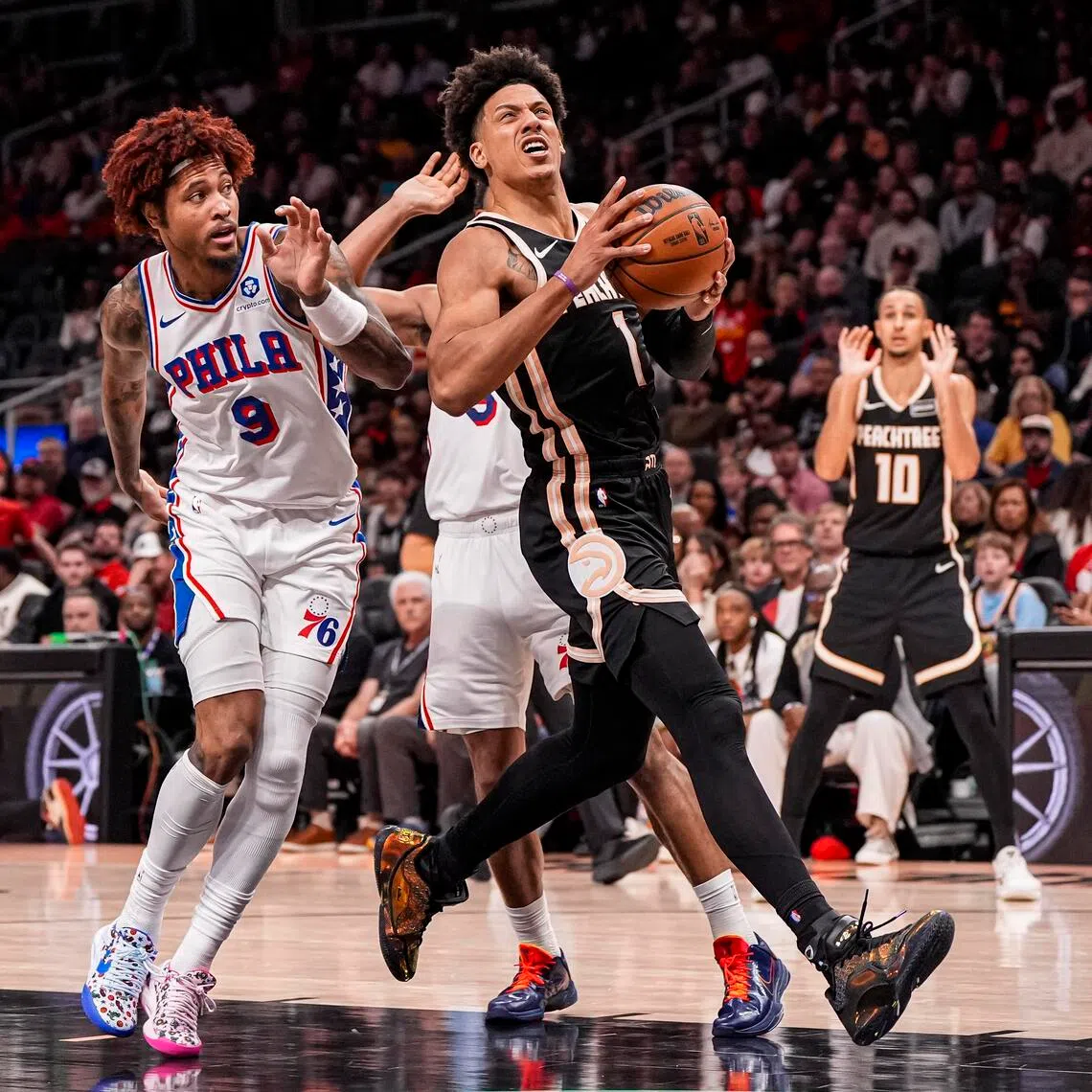 Atlanta Hawks forward Jalen Johnson drives the lane past Philadelphia 76ers forward/guard Kelly Oubre Jr. during an NBA game at State Farm Arena.