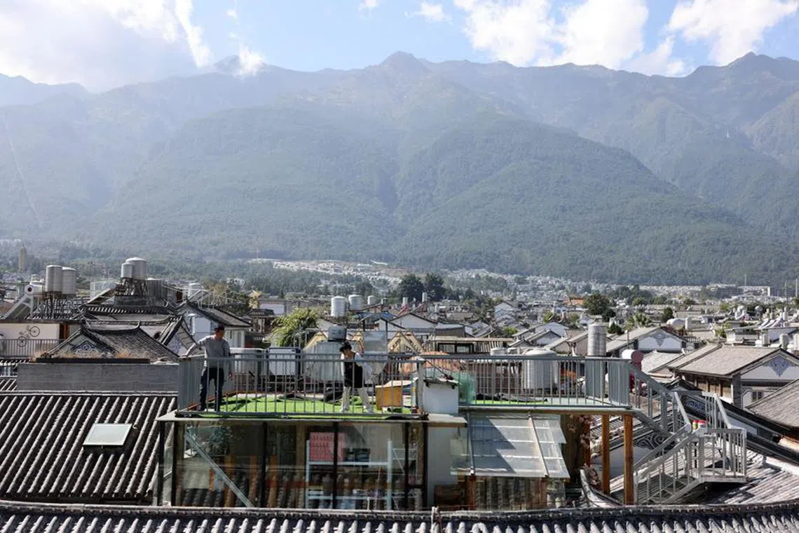 FILE PHOTO: People set up a carpet on a rooftop overlooking the old town of Dali with Cangshan mountain in the background, in Yunnan province, China November 9, 2023. REUTERS/Florence Lo/File Photo