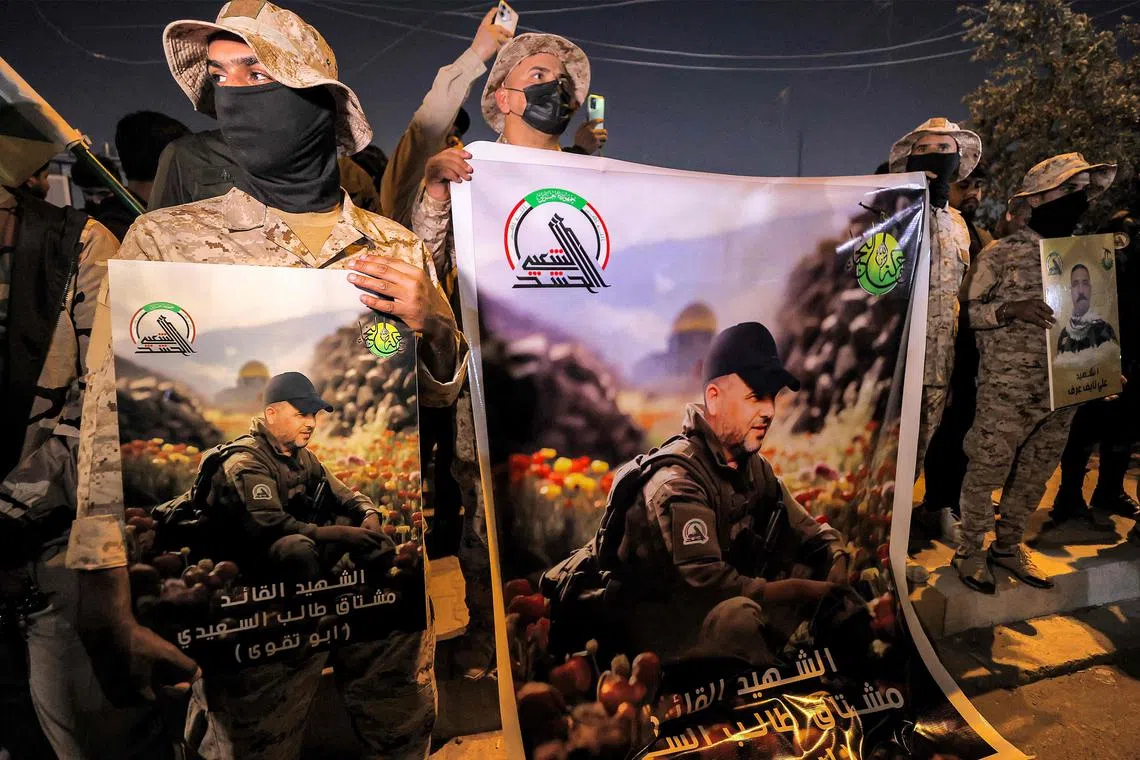 Members of Iraq's Popular Mobilisation Forces paramilitaries - of which Harakat al-Nujaba is a faction - hold signs identifying the group's slain commander, Mushtaq Talib al-Saidi, during his funeral in Baghdad.