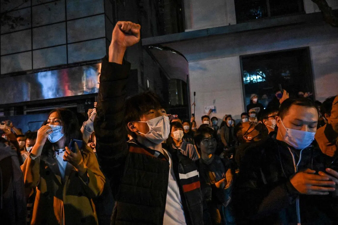 People sing slogans while gathering on a street in Shanghai on Nov 27, 2022.