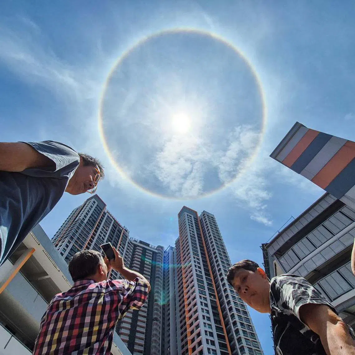 Onlookers taking photos of a sun halo at Clementi, Singapore, on Aug 25, 2025. The natural phenomenon is produced when sunlight interacts with ice crystals in the atmosphere. The crystals are made of ice rather than water droplets, due to their high altitude.
