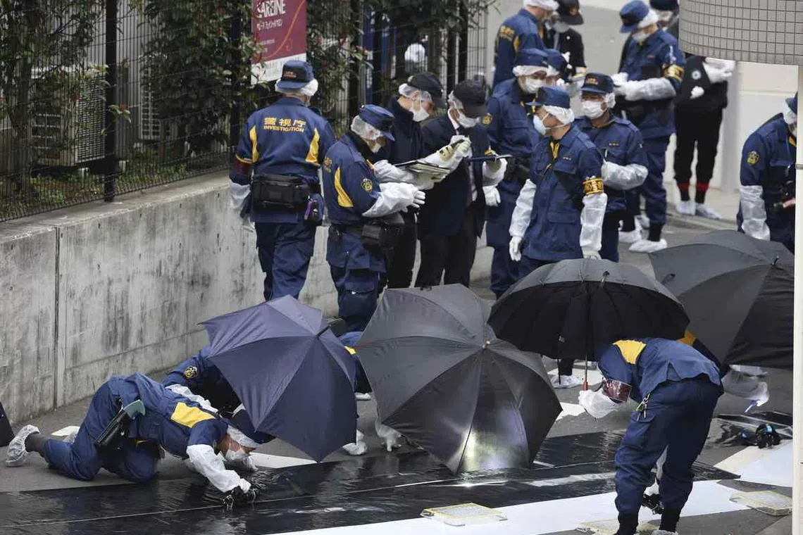 Police officers investigate the site where a woman was killed in Shinjuku Ward, Tokyo, on March 11.